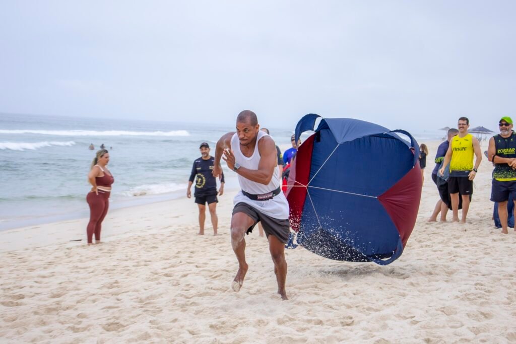 Pessoa correndo na areia com equipamento de resistência durante atividade orientada
